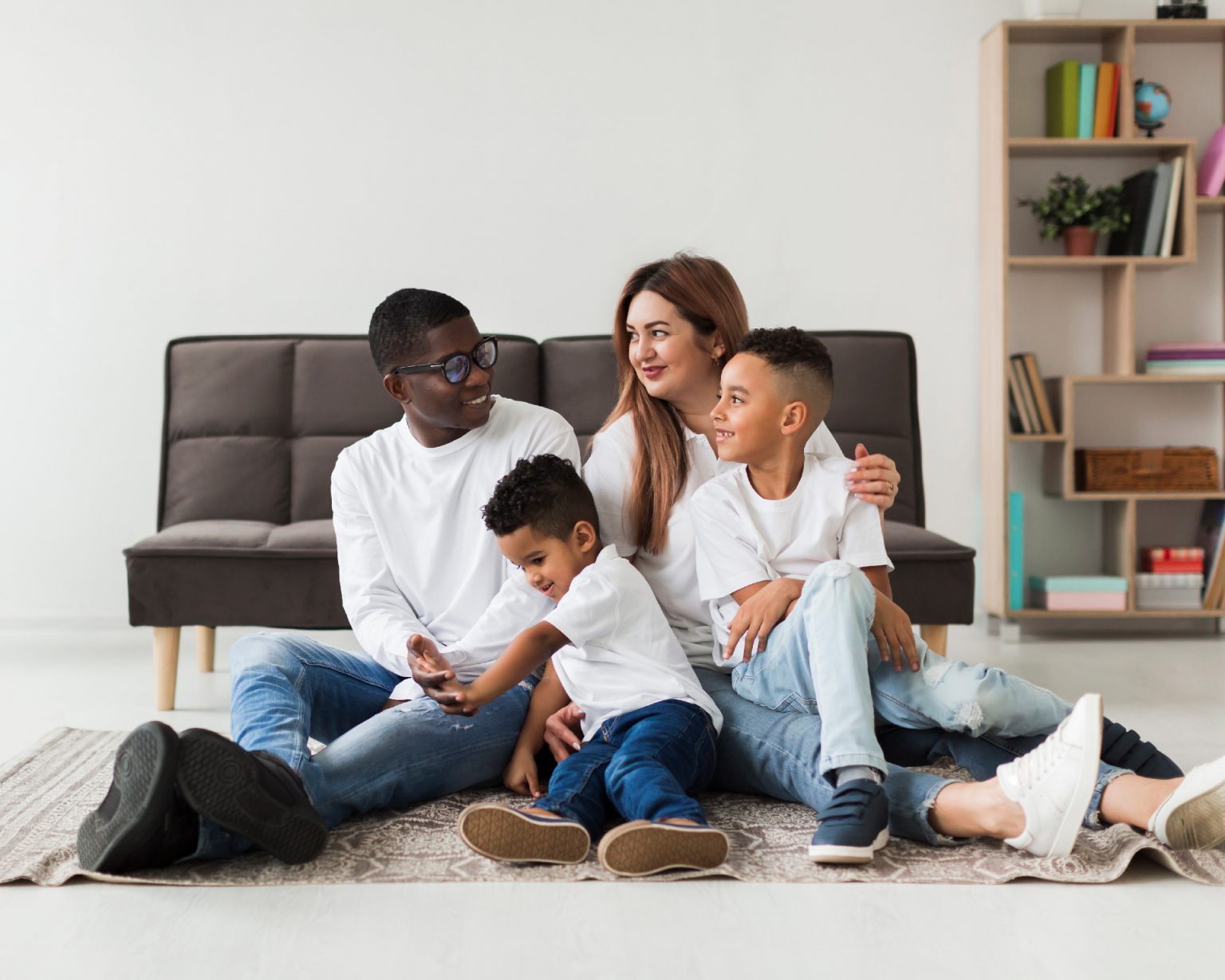 Famille heureuse allongée devant son sofa