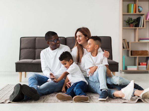 Famille heureuse allongée devant son sofa