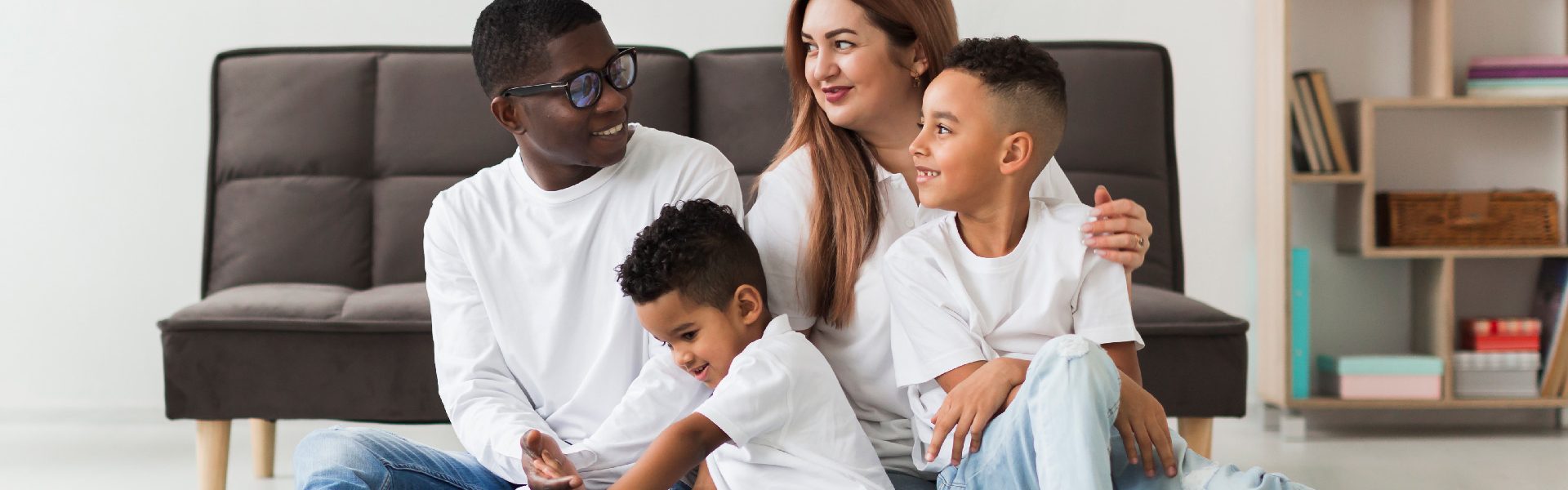 Famille heureuse allongée devant son sofa